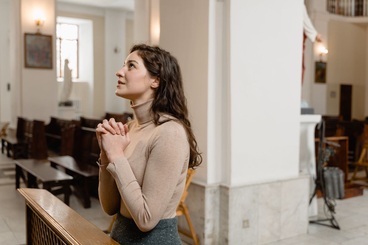 A woman deeply engaged in prayer inside a serene church setting, highlighting faith and spirituality.